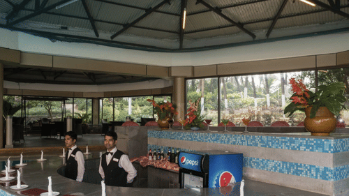 A poolside bar with stools placed in the water, glasses lined on the counter, and seating visible in the background.