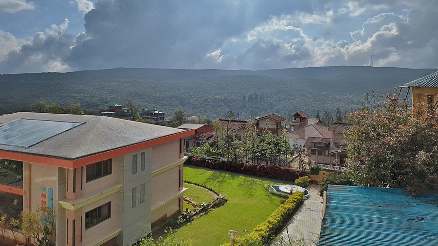 View of green hills, buildings, and a cloudy sky.