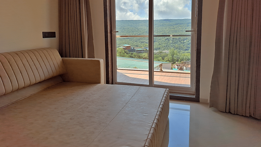 Bedroom with a cushioned sofa and glass doors opening to a balcony with a scenic view