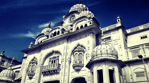 A image of a gurudwara carved out of white marble with blue sky in the background.