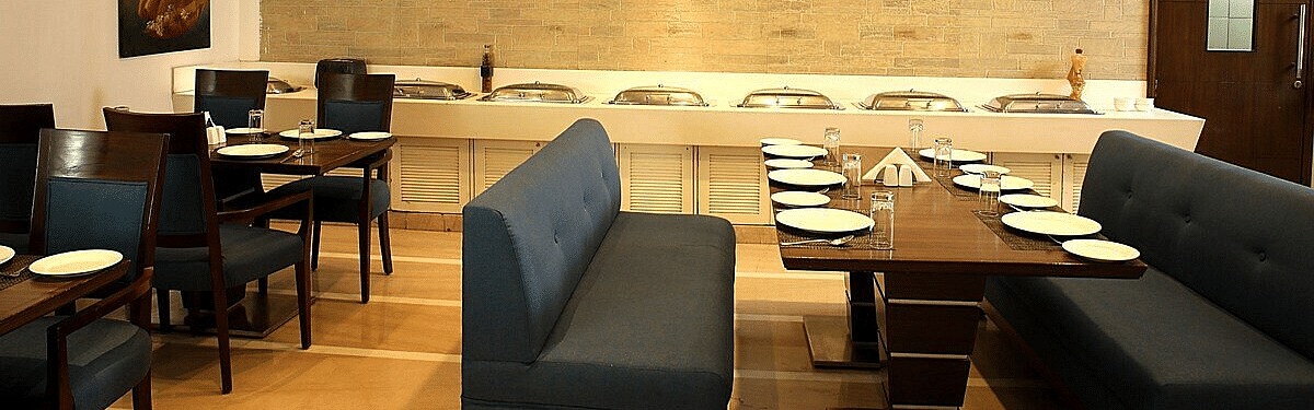 Tables and chairs neatly arranged with cutlery set on the table at Café Inde, Inde Signature Tower, Gurgaon