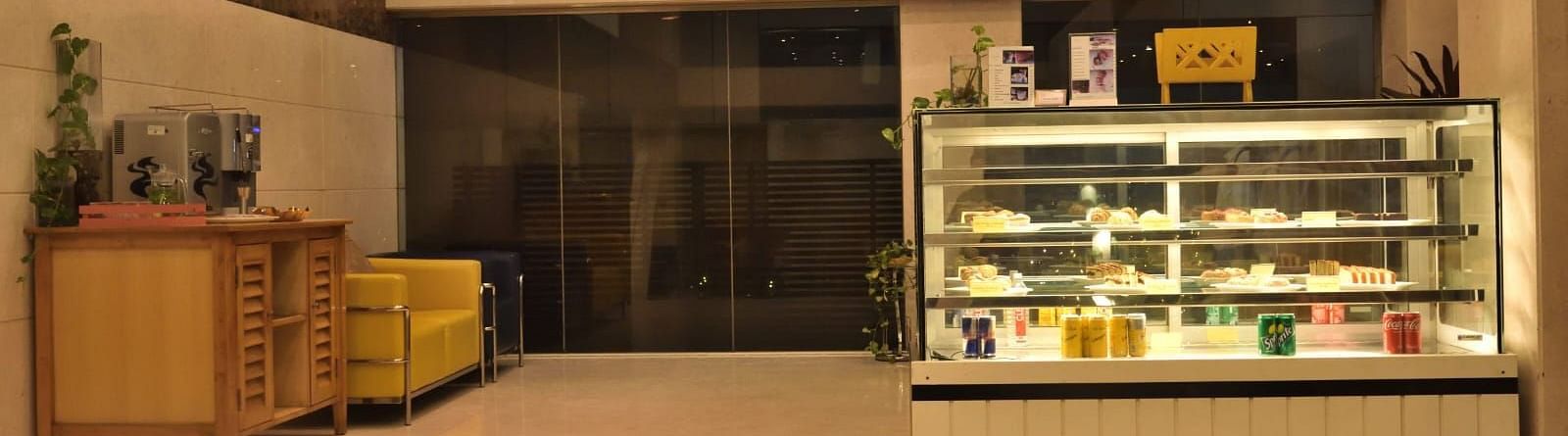 The Lobby Bake House features a display fridge with food, seating, and warm lighting, suggesting a welcoming atmosphere at The Cunningham Hotel