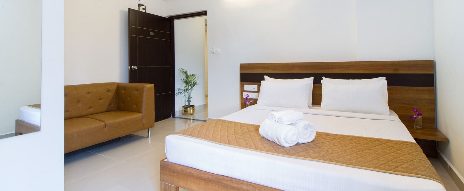 A hotel room including a double bed with bedding and an armchair at Sanctum Suites Whitefield, Bangalore.