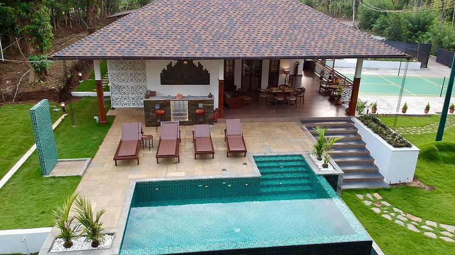 A villa with a thatched roof, private pool, and outdoor seating in a green setting - BluSalzz Collection - Tranquil Resort, Wayanad
