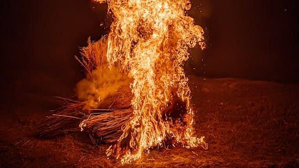 A tall flame burns against a dark background.