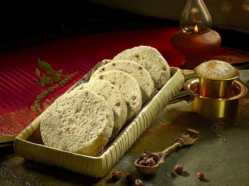 Tray of traditional Indian sweets with decorative garnishes and serving bowls.