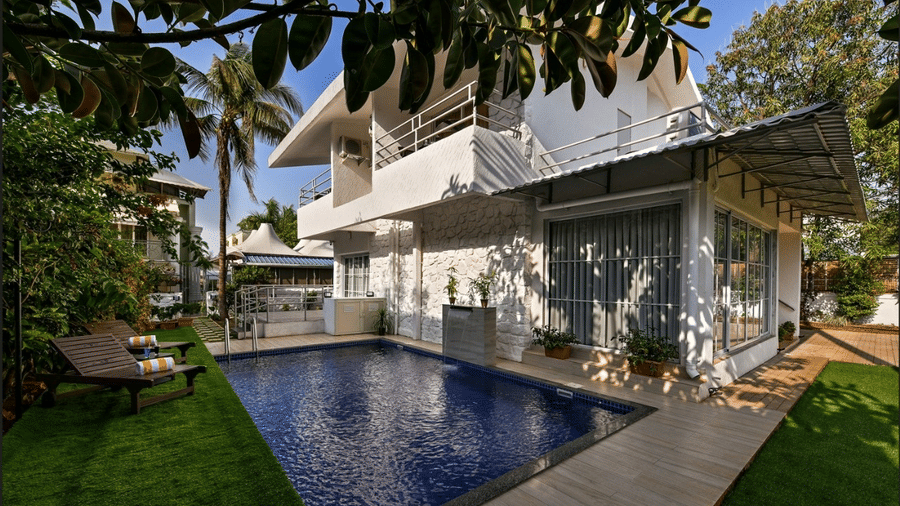 A breathtaking view of a Maxxvalue Klub Klass Villa, Lonavala featuring a stunning infinity pool, lush gardens, and modern architectural design.