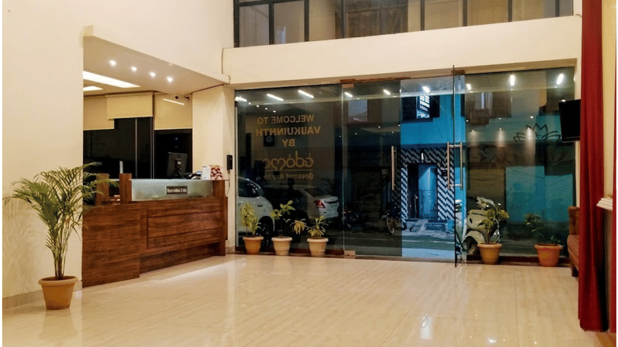 Spacious and bright hotel lobby  at Vaikunth by adamo with polished floors and potted plants near a glass entrance.