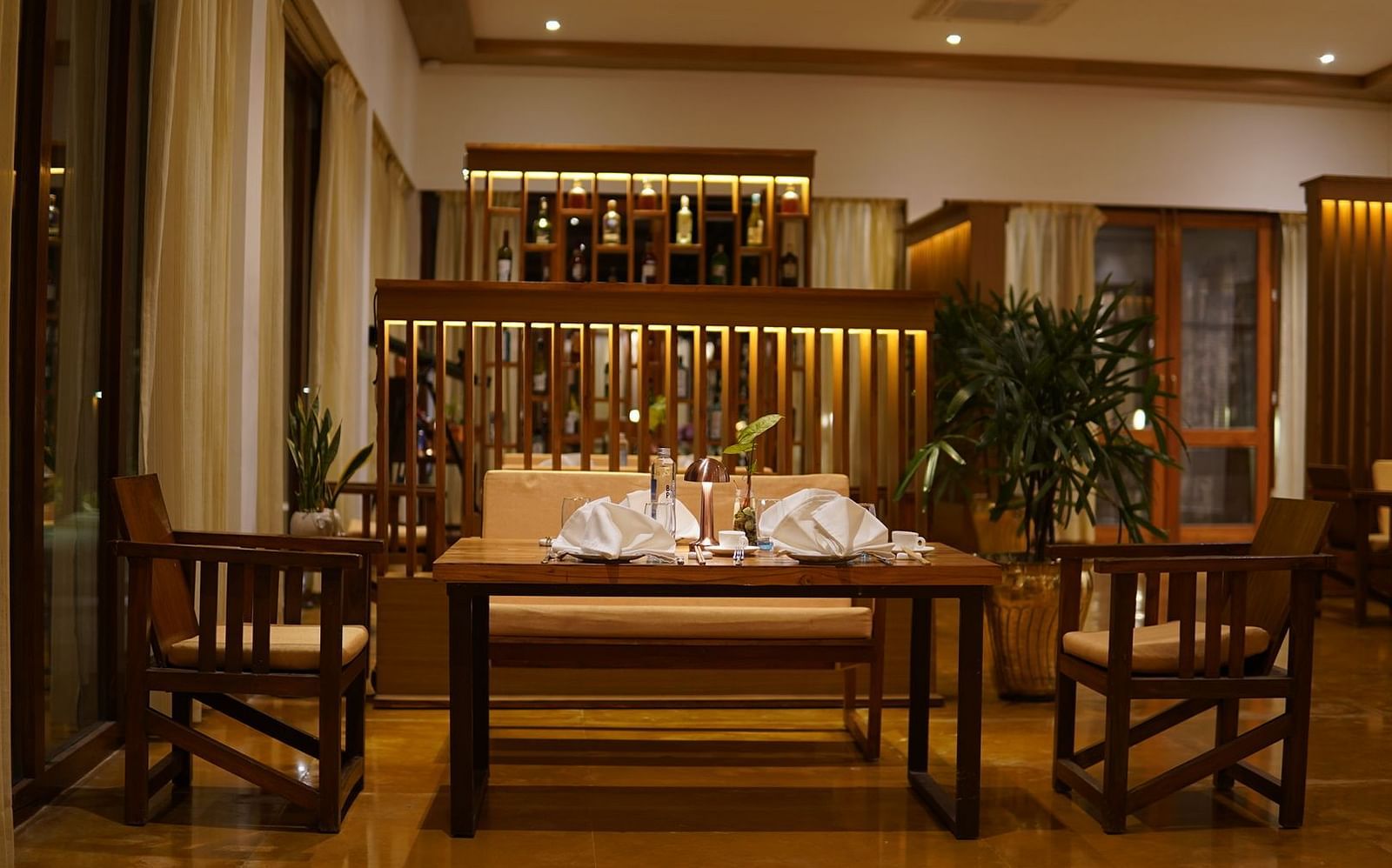 Seating arrangement at Asian Table at Saraca Resort & Spa Corbett with the bar counter in the backdrop