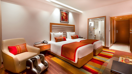 Grand Club Room with twin size beds and sofa chair at Grand Chennai By GRT Hotels.