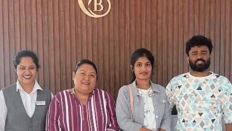 people posing for a group photo indoors in lobby area behind is a wooden wall with a logo at Coorg Orange Blossom Resort & Spa