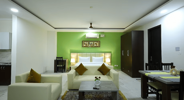 A spacious hotel room interior with a green accent wall, a sitting area and a dining table - Lime Tree Golf View, Golf Course Road