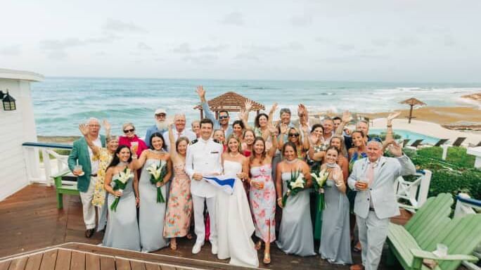 Large wedding party and guests pose on a deck overlooking the ocean at Abaco Inn.