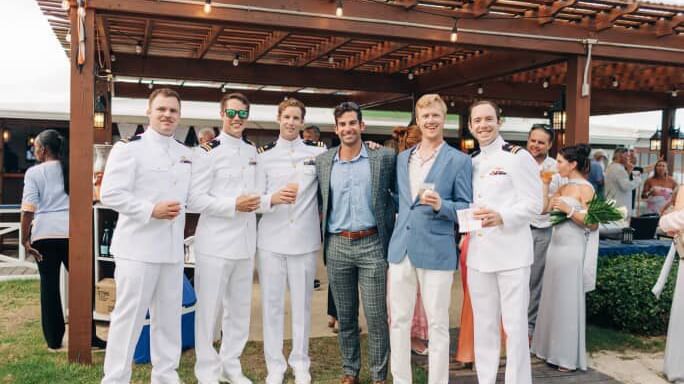 Group of men and women, some in suits and some in white shirts, pose for a photo under a wood pavilion at Abaco Inn.