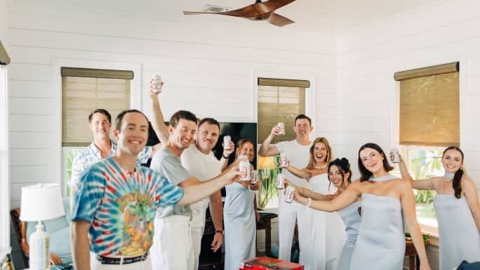Group of people hold drinks and pose together in a room at Abaco Inn during a wedding event.