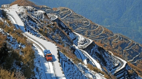 A long, winding road with switchbacks on a snowy mountain.