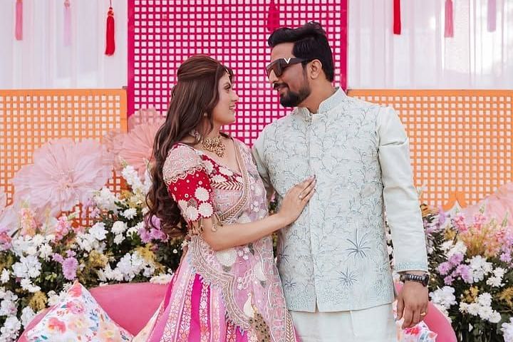 A couple in elegant traditional attire shares a loving gaze, surrounded by beautiful floral décor and a stylish setup. - Umaid Palace - A Lakeside Heritage Palace Resort