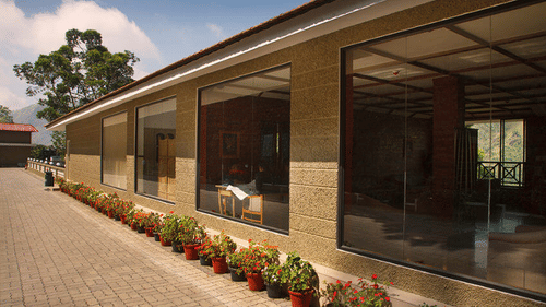 Abad Copper Castle exterior with a covered walkway, large glass windows, and potted plants line the walkway.
