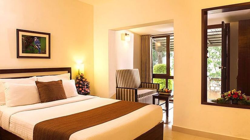 A double bed with lamps on the side inside Balcony View Room - Abad Copper Castle, Munnar