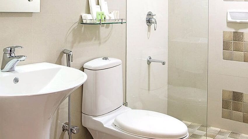 A clean, modern bathroom with a white toilet, sink, and a glass-enclosed shower - Abad Copper Castle, Munnar
