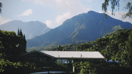A small house in a mountainous landscape with a lawn in front.