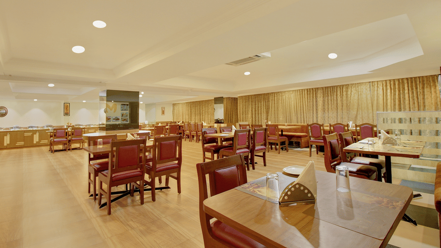 closer view of wooden furniture at coffee shop restaurant with glass tables and soft white lighting - the monarch hotel