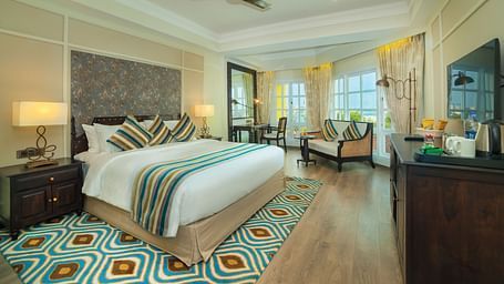  Spacious room with a large bed neatly arranged with cushions and blankets, surrounded by wooden furniture