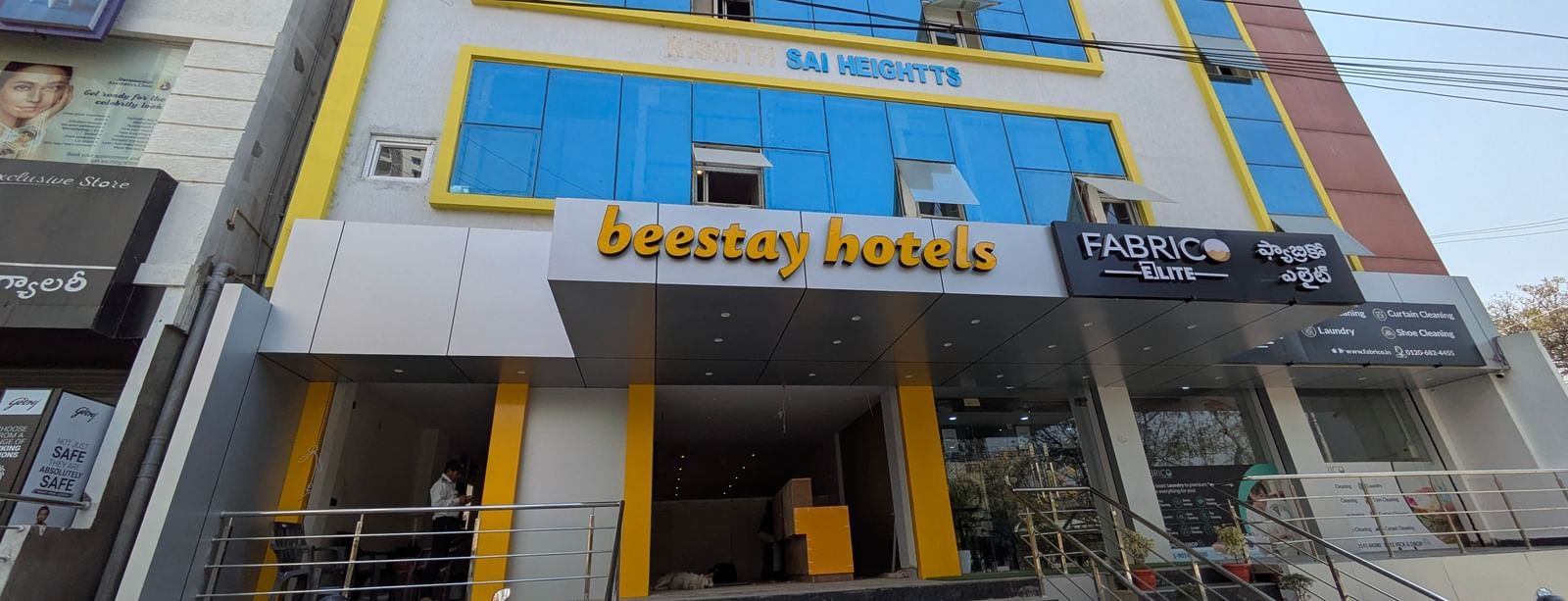 Close up  view of a multi-story building with blue-tinted windows and Beestays Hotels written on the facade - Beestay Hotels Financial District, Hyderabad 