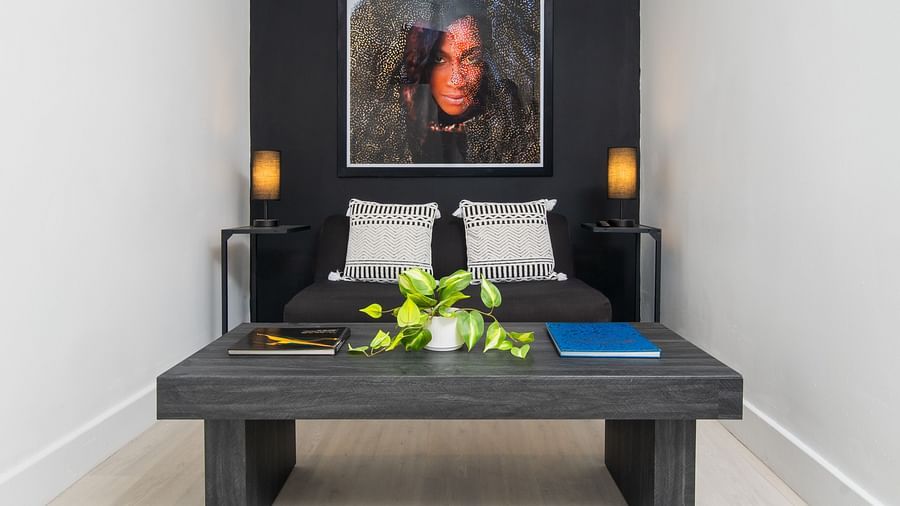 A seating area with a couch, a wall-mounted painting and a teapoy in our suite in Montego Bay