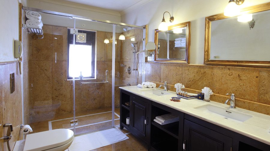 Modern bathroom in Juna Mahal deluxe room featuring a bathtub, large mirror and premium fittings designed for a comfortable stay