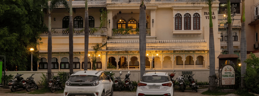 A facade of Panna Vilas Palace, featuring cars parked infront the building