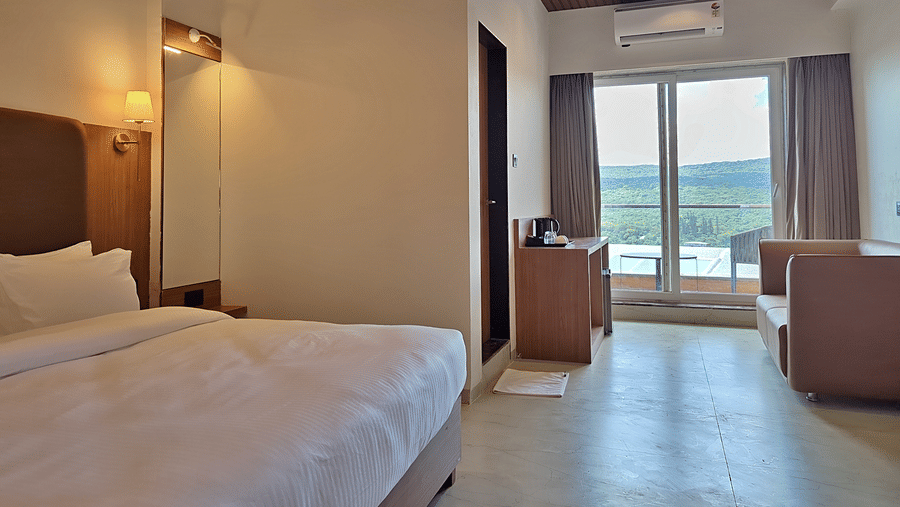 Bedroom with a double bed, padded headboard, seating, and balcony access