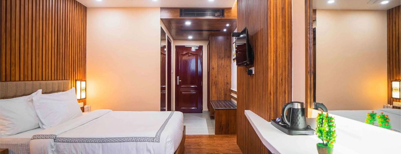 A well-furnished room at Mansha Palace offers a comfortable bed, wooden walls, a mirror, and a beverage station.