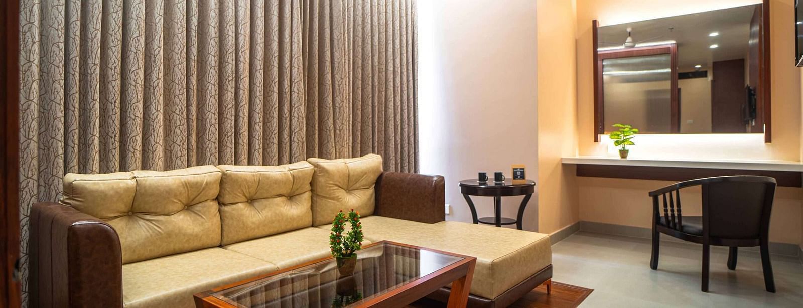A comfortable living area at Mansha Palace features a plush sofa, a glass-topped coffee table, and a vanity with a mirror.