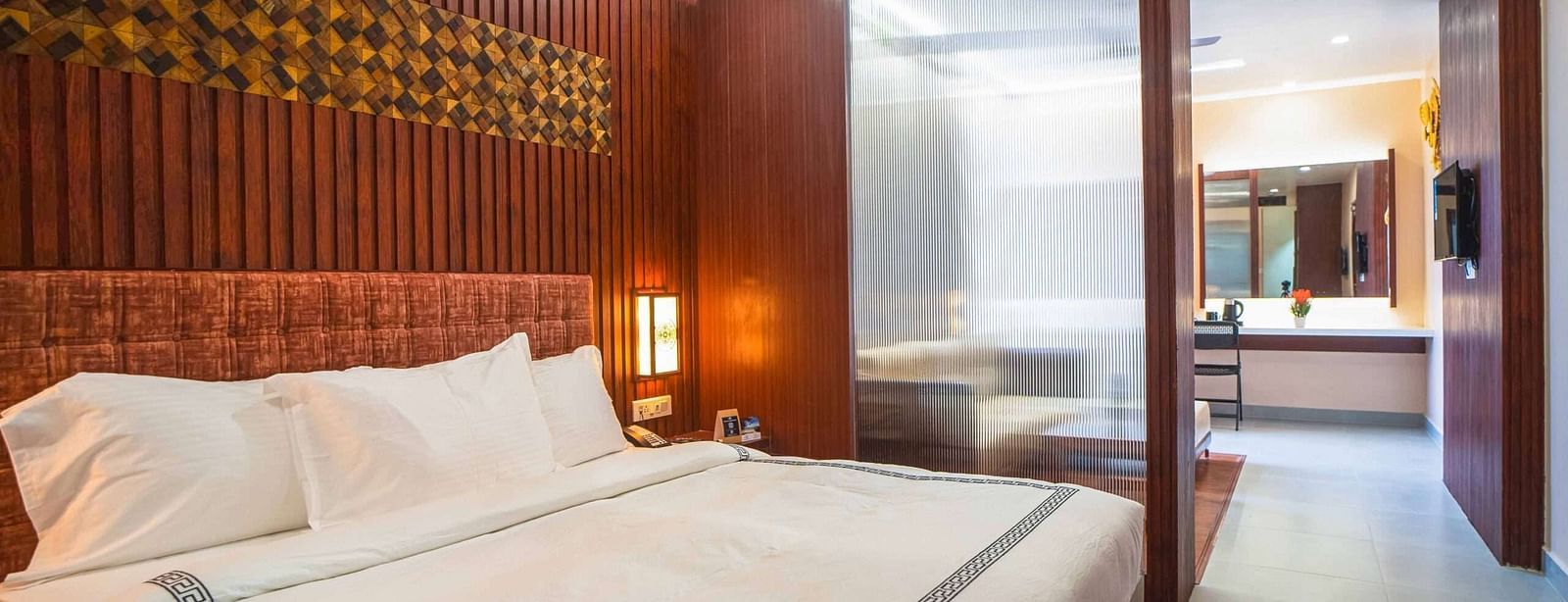 A stylish bedroom at Mansha Palace features a comfortable bed and a partial view into an adjacent area with a desk.