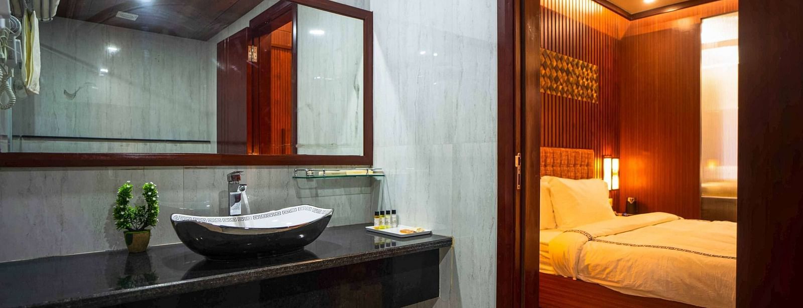 A modern bathroom at Mansha Palace features a sleek countertop with a vessel sink, a large mirror, and an open doorway to the bedroom.