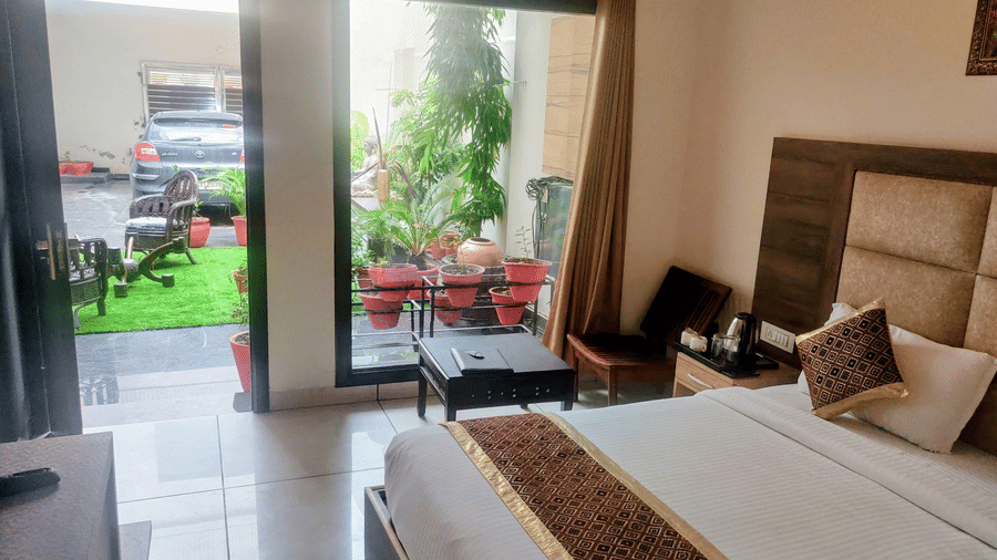 Hotel Exotic, Amritsar features a bedroom with a double bed, seating area and glass doors opening to an outdoor space.