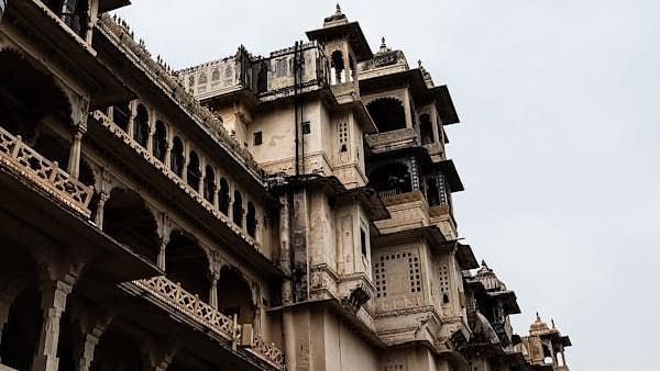 A multi-story building with balconies and a cloudy sky above.