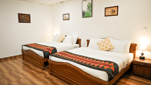 Bedroom with pillows and illuminated yellow lamps on each sides at Ibex Resorts, the best resort in Valparai.