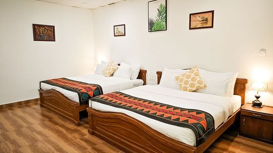 an image of a bedroom with pillows and illuminating yellow lamps on each sides at Ibex Stays & Trails, Valparai (Mistly)