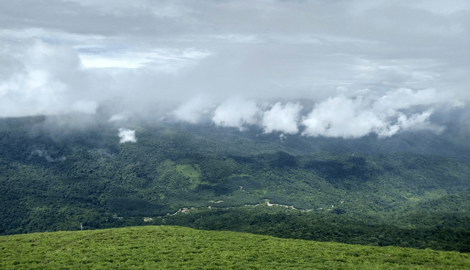 Expansive view of mist-covered hills and valleys under a cloudy sky, showcasing natural beauty.