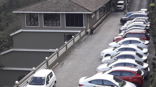 A high-angle view of a parking lot filled with white cars - Abad Copper Castle, Munnar