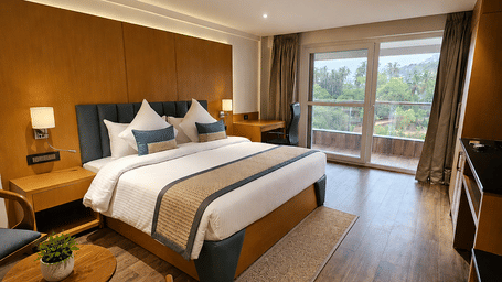 Executive Suite bedroom featuring a large bed, wooden floors, and glass doors leading to a balcony at BluSalzz Collection - Casa Onze, Arpora.