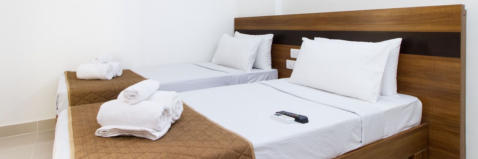 A hotel room offering two single beds both with brown bedding at Sanctum Suites Whitefield, Bangalore.