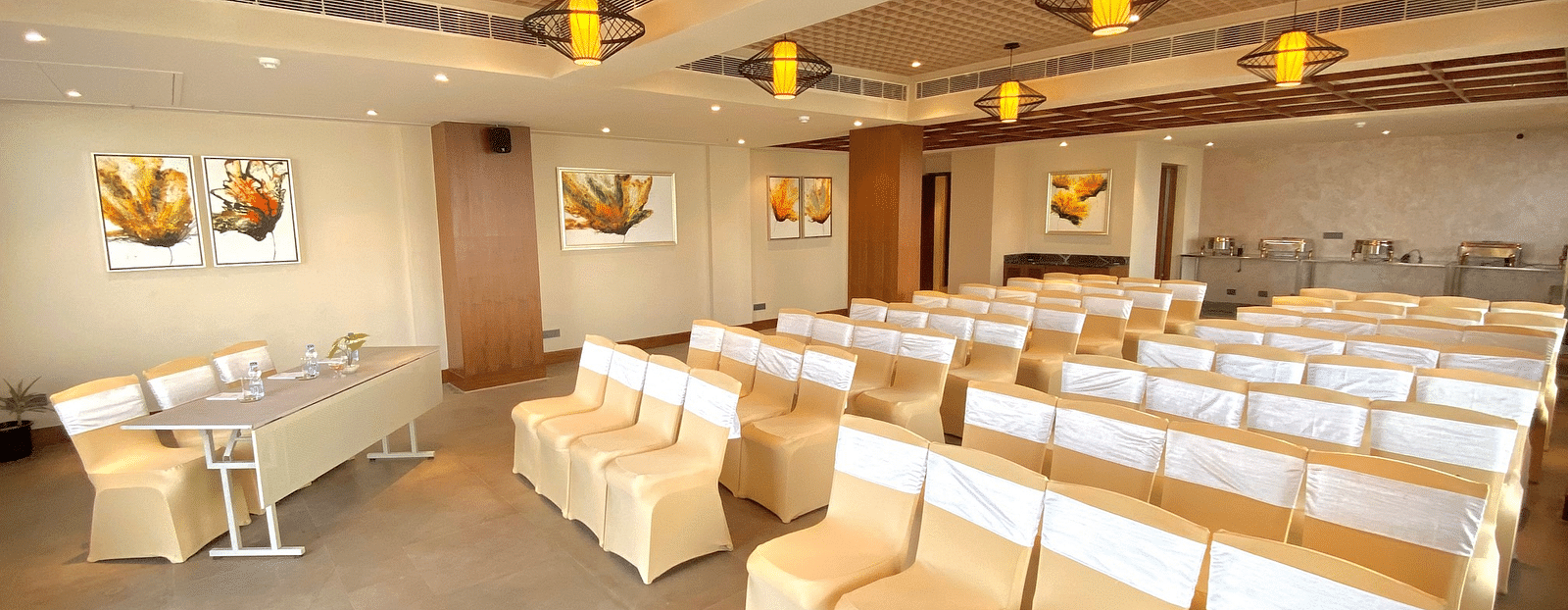 An image of a banquet hall with its seating arrangement and subtle decoration with lighting - Hideaway banquets & Lawns, Greater Noida
