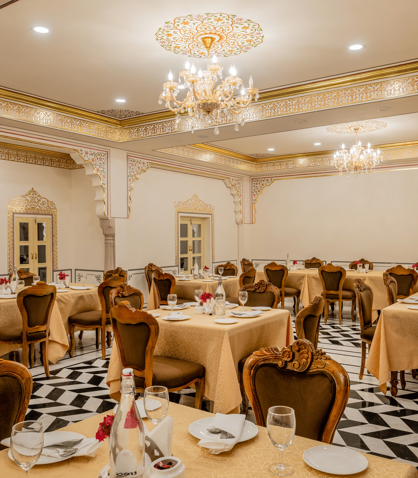 side view image of the dining area with well arranged crockery along with a small flower vase with rose kept in it - Brij Castle, Jaipur