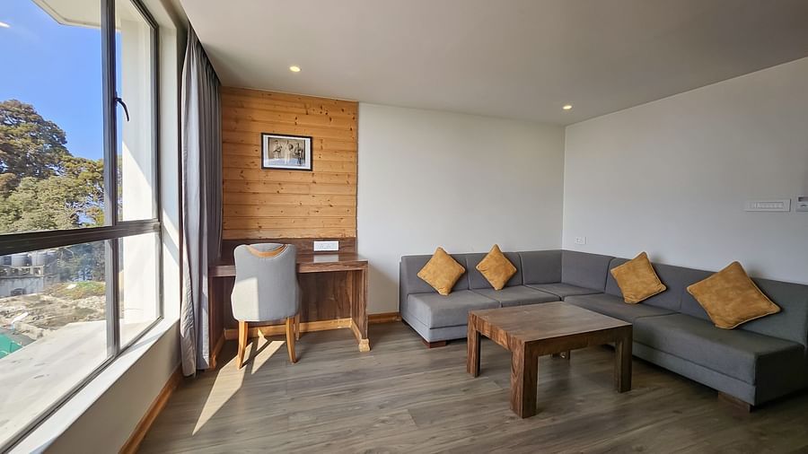 An image of a premium suite with a sofa set, table, work desk, chair, and expansive window overlooking the view - Yashshree Sanderling, Darjeeling
