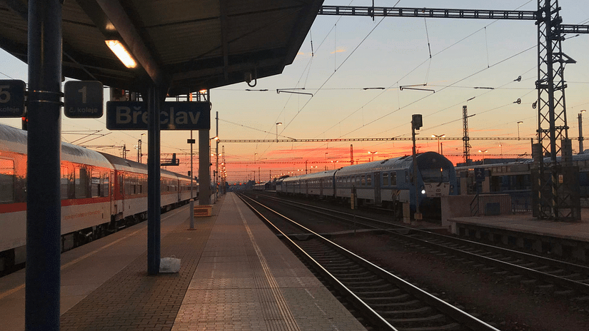 An overview of a train station with different hues in the sky in the background