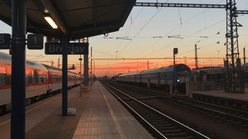An overview of a train station with different hues in the sky in the background