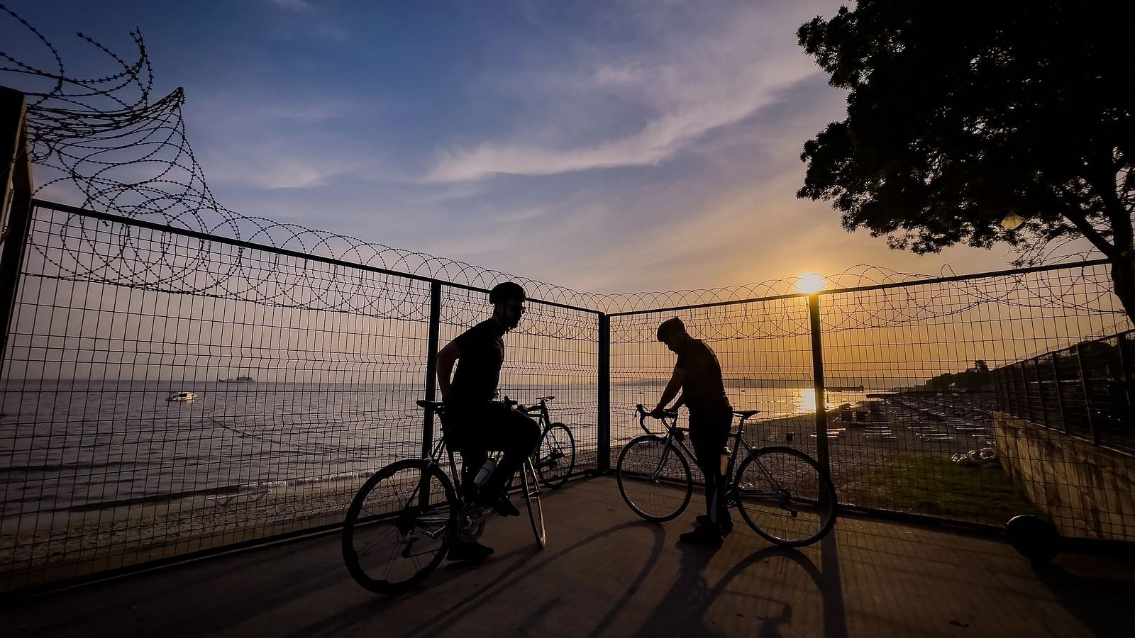 Two bicycles are parked, with two people sitting on it.